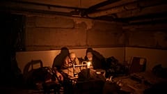 Dos mujeres iluminadas por una vela se esconden en un sótano utilizado como refugio antibombas en Irpin, en las afueras de Kiev, Ucrania