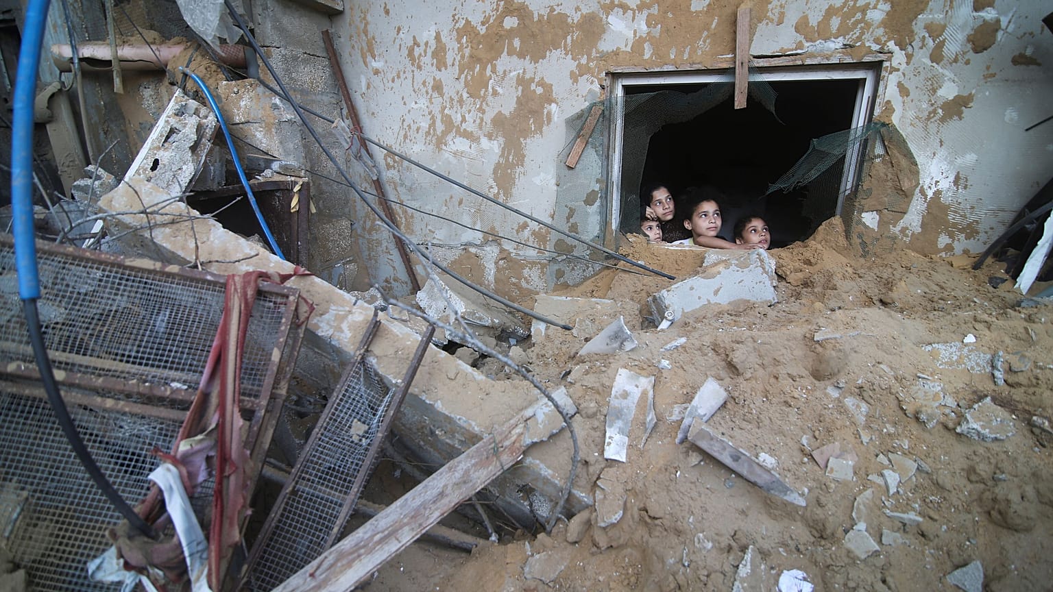 أطفال فلسطينيون ينظرون إلى مبنى عائلة زنون الذي دمرته الغارات الجوية الإسرائيلية في رفح بقطاع غزة