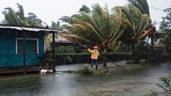 A man fixes the roof of a home surrounded by floodwaters brought on by Hurricane Eta in Wawa, Nicaragua.