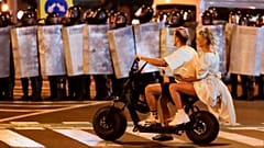 A rendőrsorfal előtt motorozik egy fiatal pár Minszkben