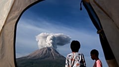 Indonesian children watch Mount Sinabung erupting in Karo, North Sumatra, Indonesia. March 11, 2021