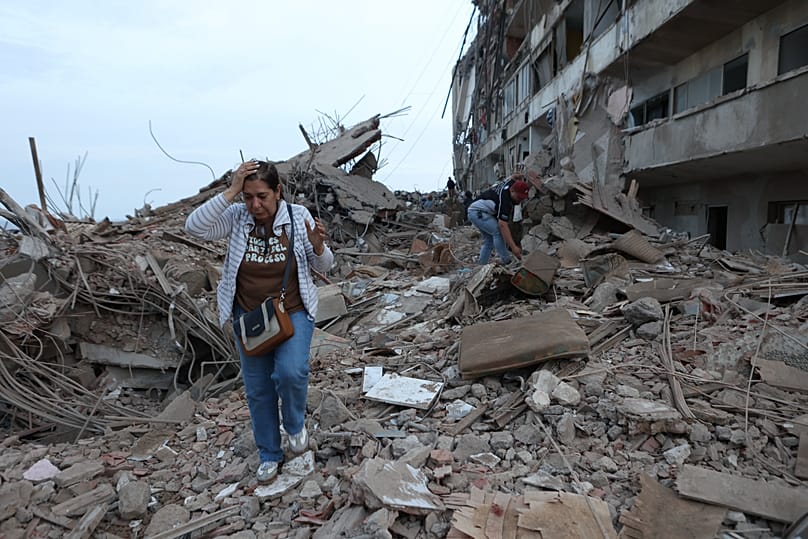 Residentes caminan entre los escombros de edificios dañados por los terremotos del día anterior en Catia La Mar