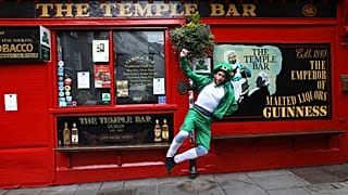 Egy férfi Szent Patrik napi öltözékben Dublin legendás pubja, a Temple Bar előtt