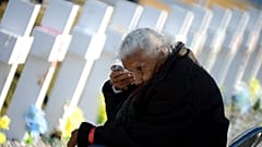 Una anciana llora junto a una de las tumbas