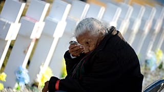 Una anciana llora junto a una de las tumbas
