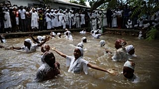 Mulheres banham-se numa piscina sagrada em aparente transe