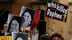 People hold up photos of assassinated anti-corruption journalist Daphne Car