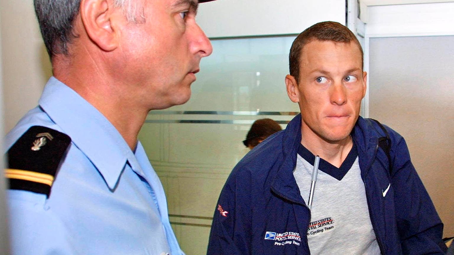 Lance Armstrong 2001-ben egy csendőr mellett a grenoble-i repülőtéren