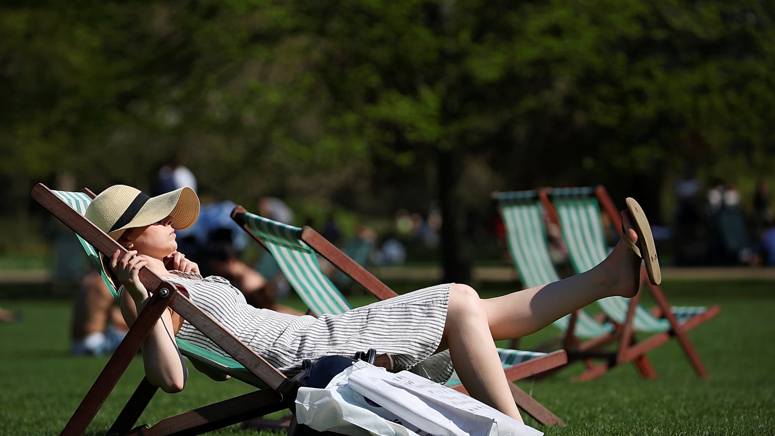 Londra'da St James Parkı'nda şezlonglarda güneşlenen bir kadın