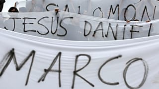 Demonstrators hold canvas with the names of the three film students