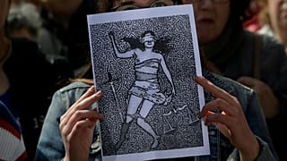 A woman holds up a picture as other shout slogans during a protest 