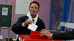 Um tunisino deposita o voto numa urna de Tunis