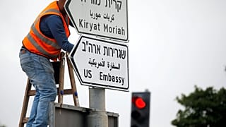Ein Arbeiter bringt eines der Straßenschilder an