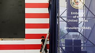 Ein Mann arbeitet vor den Streifen einer USA-Flagge.