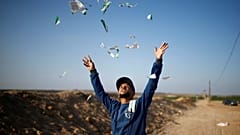 شاب فلسطيني ينثر منشورات مزقها بعد أن ألقاها الجيش الإسرائيلي على قطاع غزة 