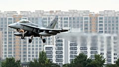 Ein Kampfjet vor Häuserkulisse.