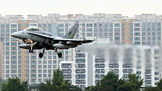 Ein Kampfjet vor Häuserkulisse.