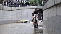 Man carries a woman on his shoulders at a flooded street