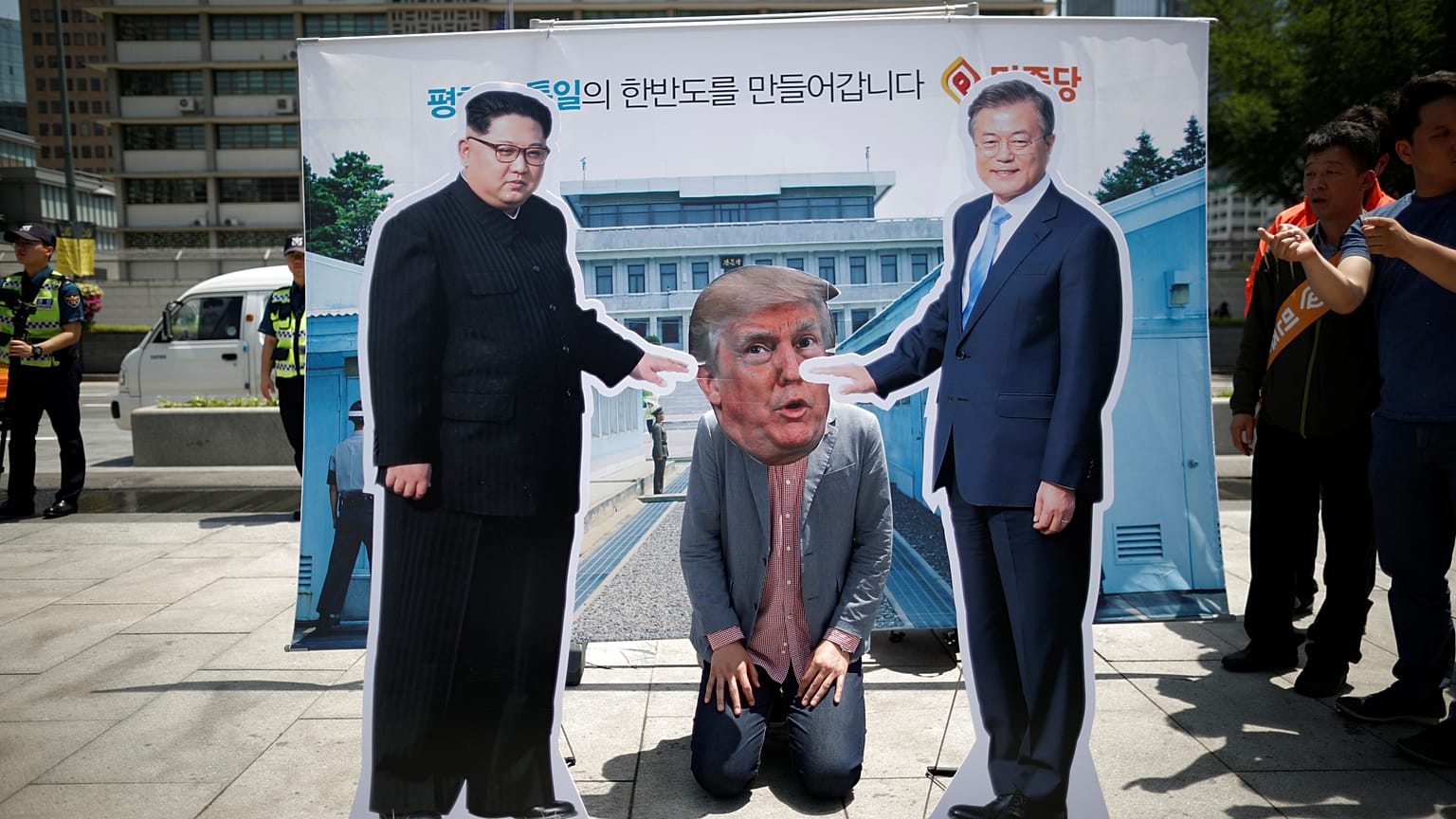 A man wearing a mask of U.S. President Donald Trump kneels down between cut