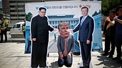 A man wearing a mask of U.S. President Donald Trump kneels down between cut