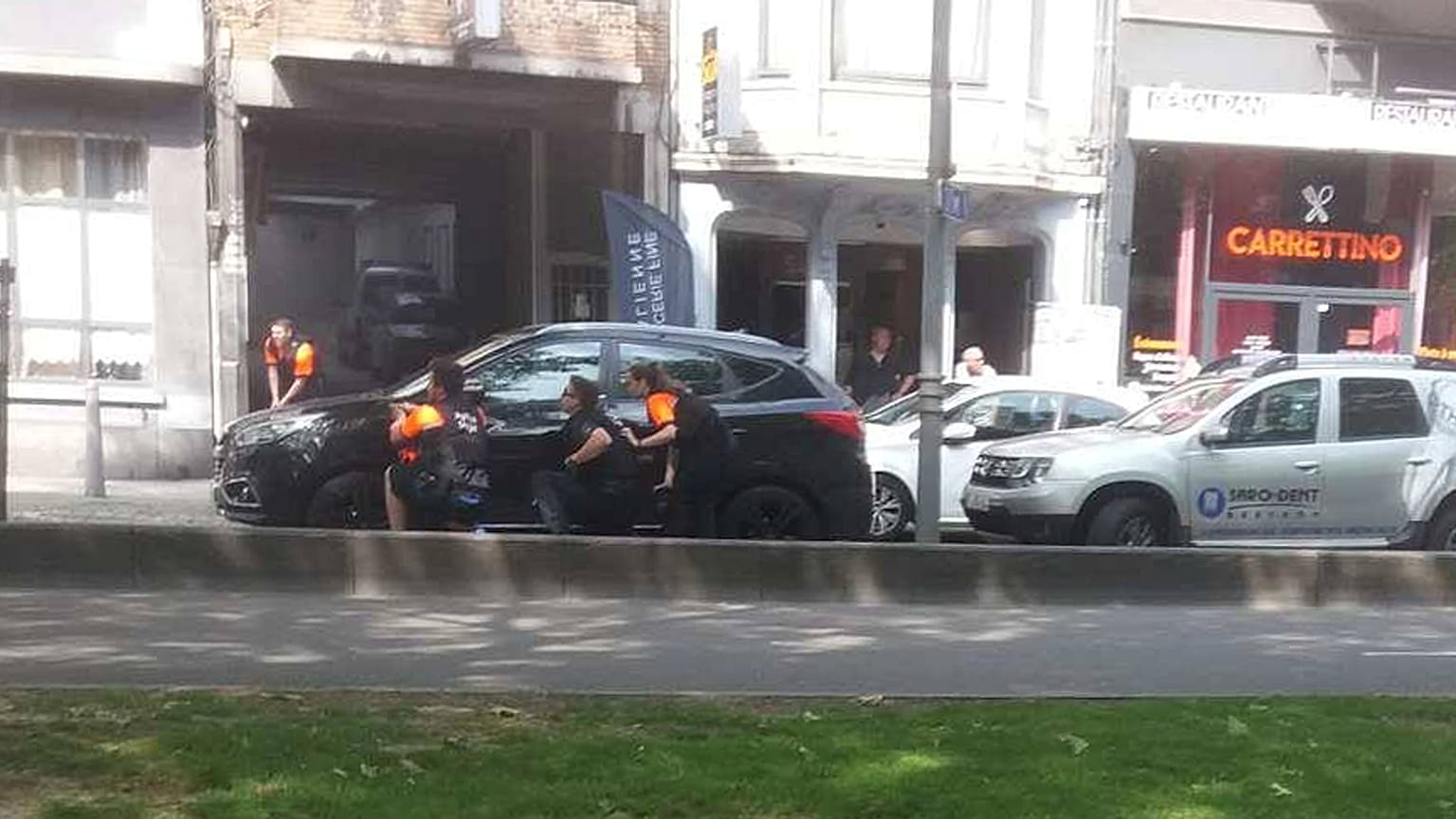 Police officers shelter near the scene of the shooting