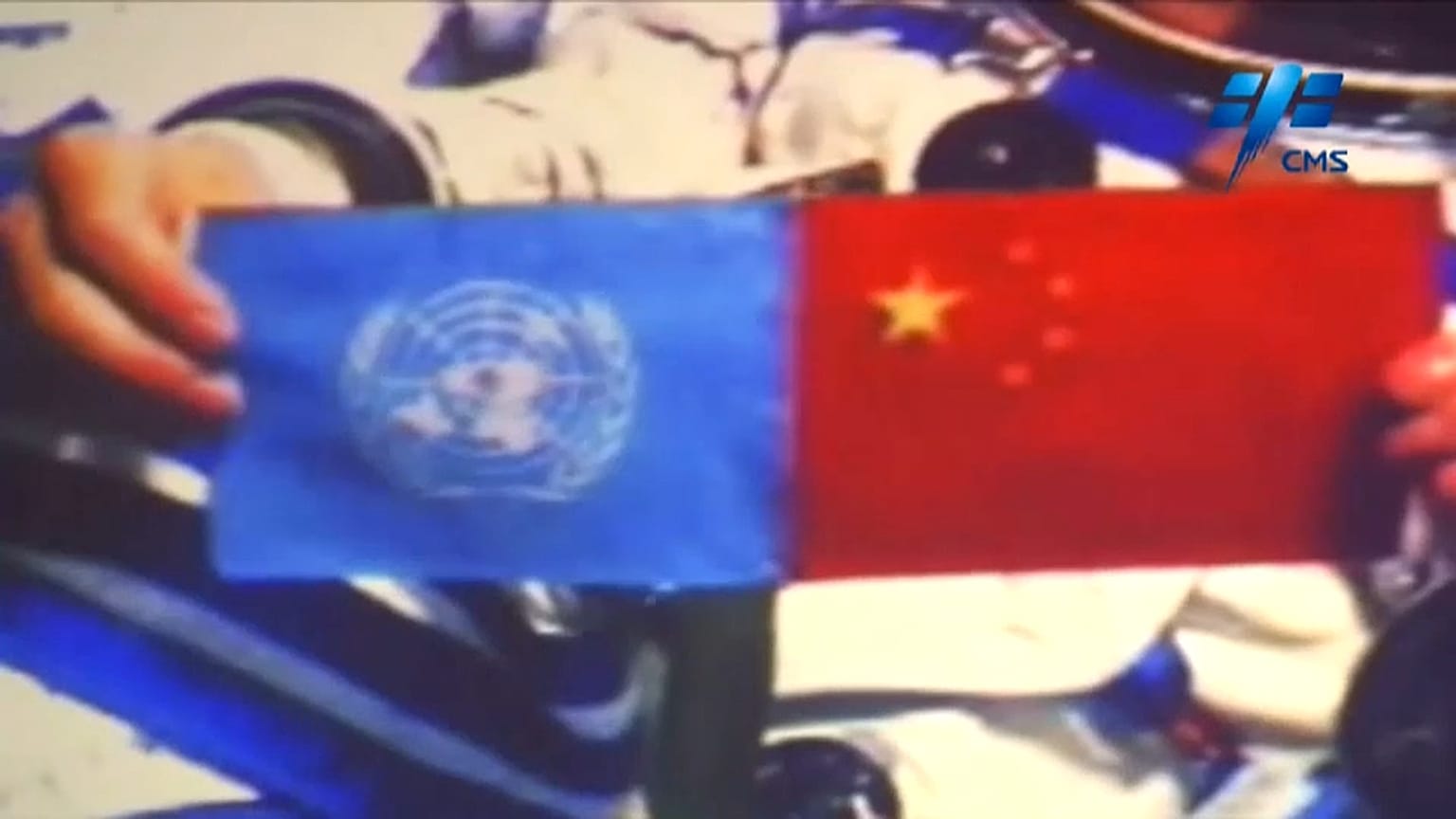 Chinese astronaut holds up the flags of the United Nations and China