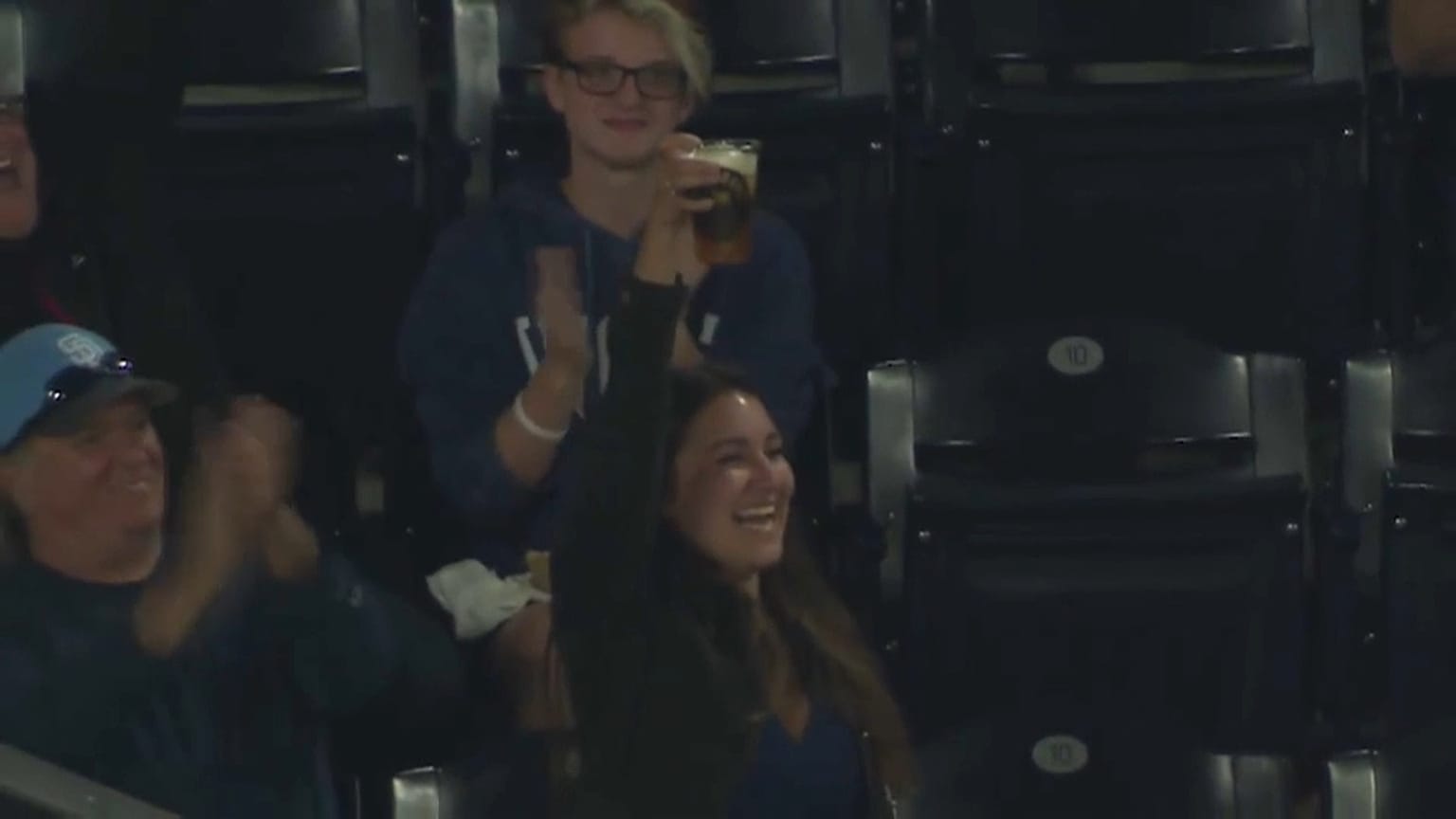 A baseball fan celebrates catching the ball with her beer