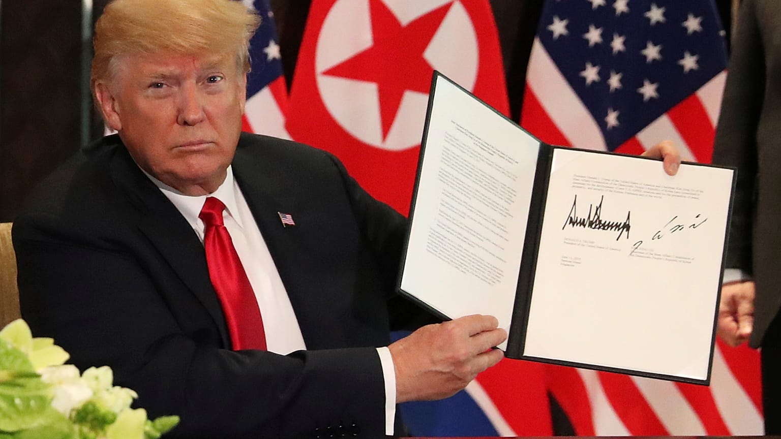 Donald Trump holds up the signed document