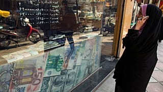 Une femme regarde les taux de change dans une boutique à Téhéran. 