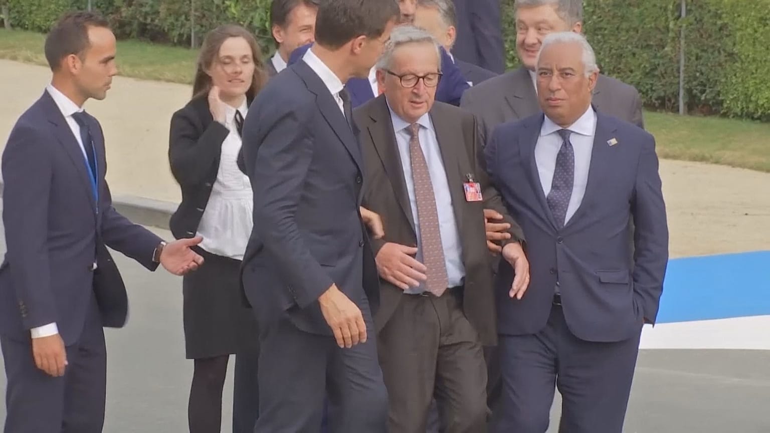 EU-Kommissionspräsident Jean-Claude Juncker gestützt von anderen Männern