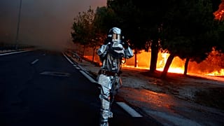 Un pompier en équipement lutte contre les incendies près d'Athènes, Grèce