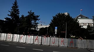 Police stands near a barrier with the word 'dictatorship' written on it