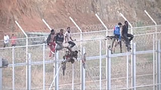 مهاجرون يتسلقون السور الحدودي