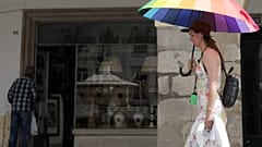 Turista passeia protegida por uma sombrinha em Évora