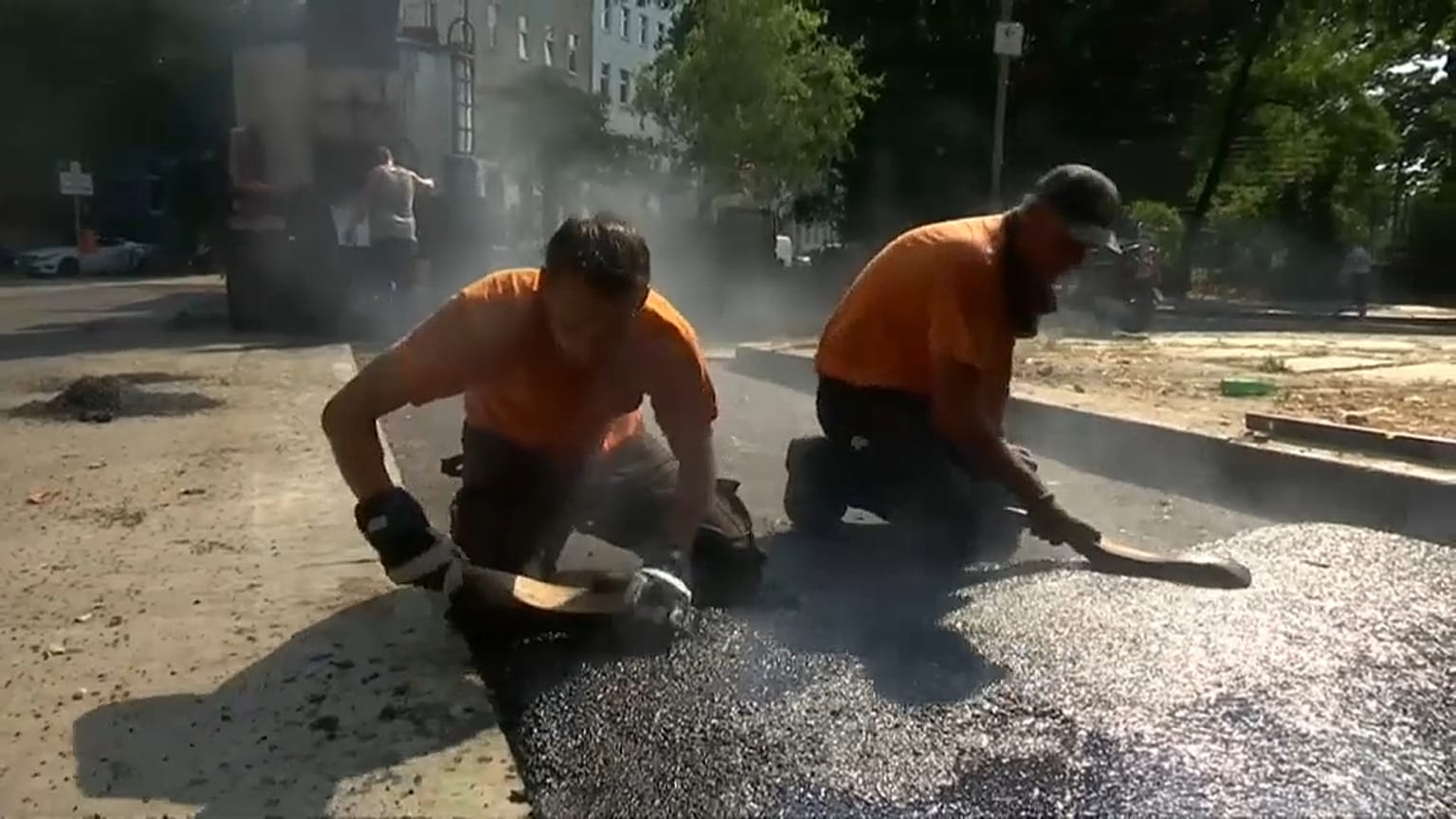 Ein echter Knochenjob: Heißen Asphalt auf der Straße verteilen.