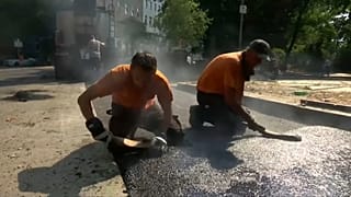 Ein echter Knochenjob: Heißen Asphalt auf der Straße verteilen.