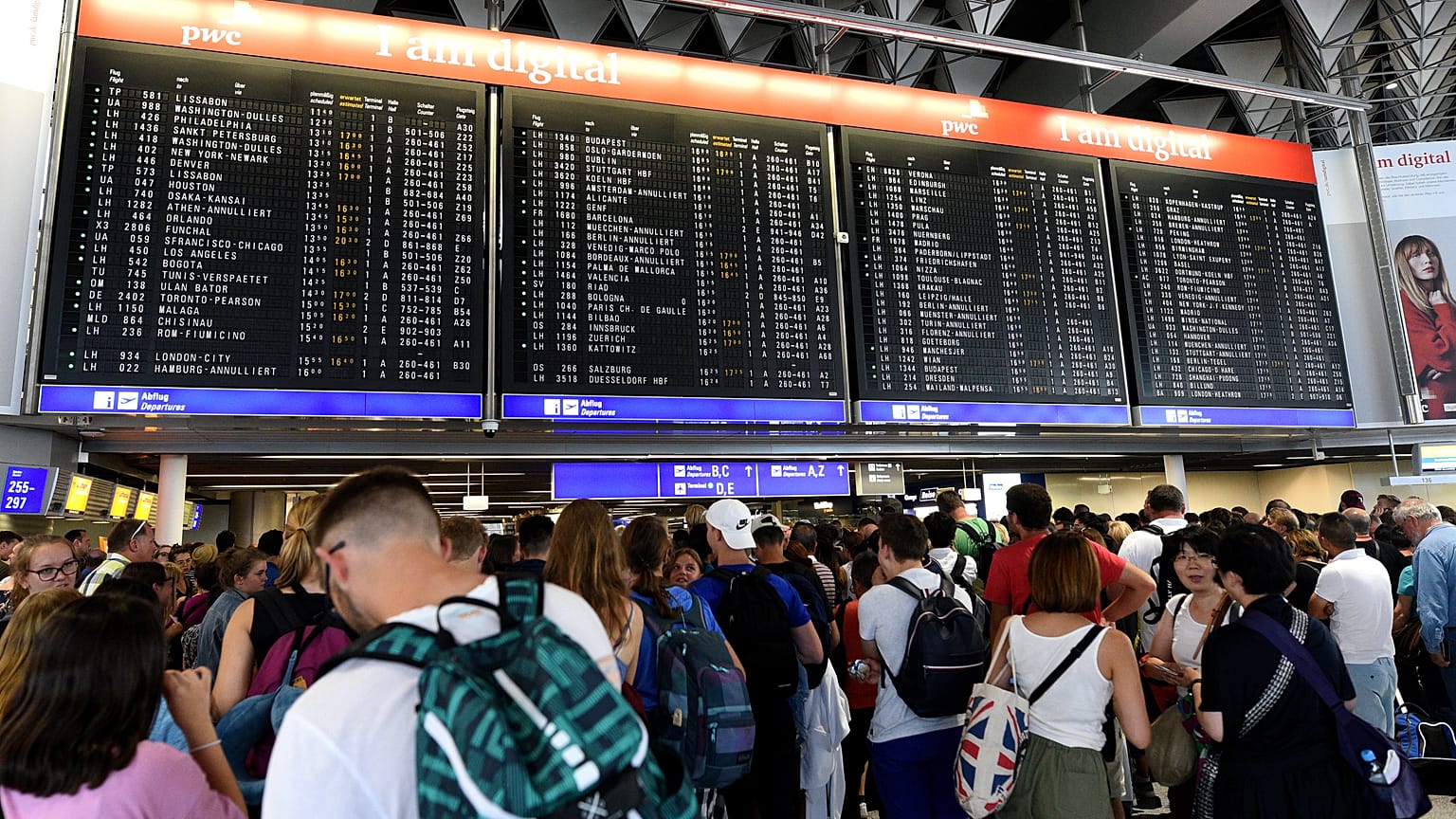 Reisende warten am Flughafen Frankfurt vor der Anzeigetafel