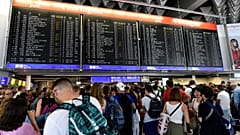 Reisende warten am Flughafen Frankfurt vor der Anzeigetafel