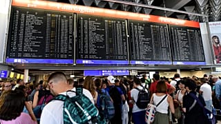 Reisende warten am Flughafen Frankfurt vor der Anzeigetafel