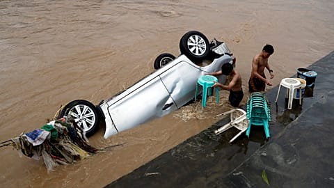 Einwohner reinigen Stühle neben einem überfluteten Auto