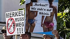 "Burka? Biz bikiniyi tercih ederiz" ve "Merkel ayrılmalı" yazılı posterler