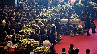 Mit Blümen geschmückte Särge bei der Trauerfeier