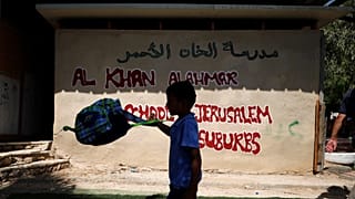 یک کودک فلسطینی در کنار مدرسه خان‌الاحمر