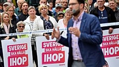 Voters look on as Sweden Democrats leader Jimmie Akesson gives a speech