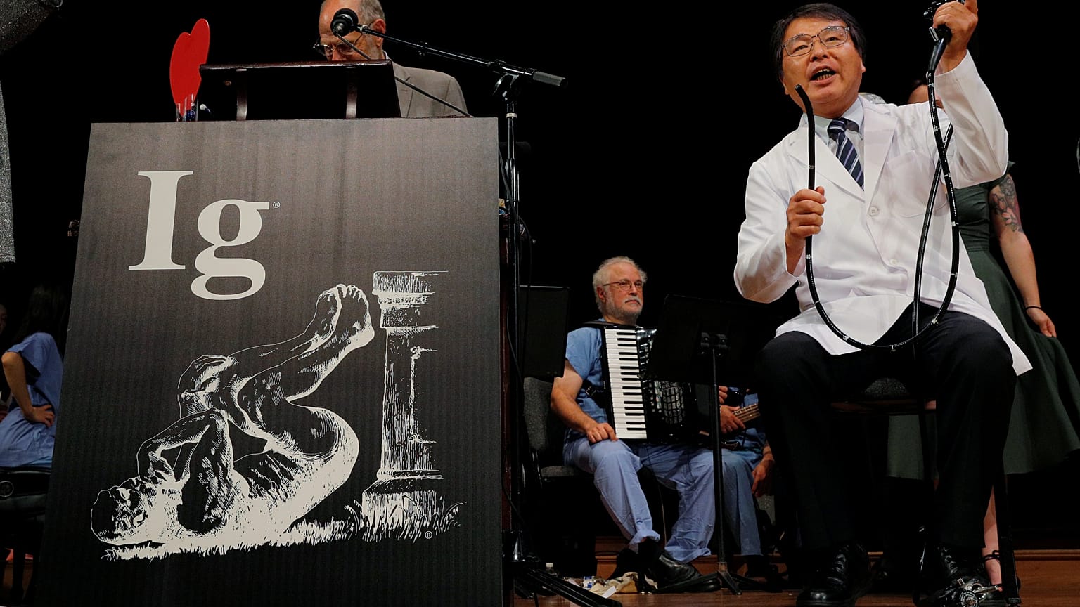 Akira Horiuchi (R) demonstrates his research at the 2018 IG Nobel ceremony.