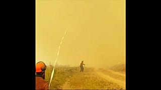 Un tornado de fuego absorbe la manguera de un equipo de bomberos 