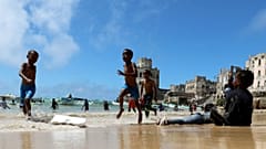 Crianças brincam em Mogadíscio, Somlia, na rebentação do oceano Índico