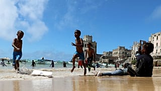 Crianças brincam em Mogadíscio, Somlia, na rebentação do oceano Índico