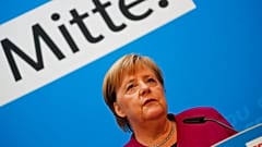 Angela Merkel bei einer Rede; im Hintergrund das Wort "Mitte"