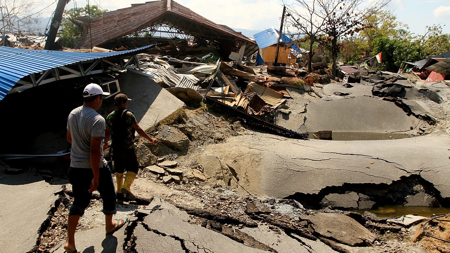 People walk in an area hit by an earthquake in Palu, Indonesia